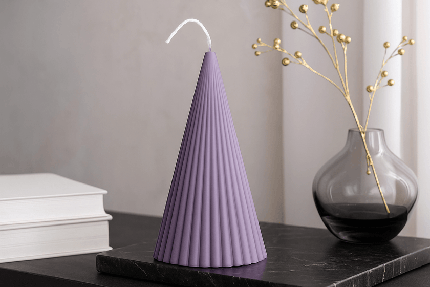 Purple textured candle on a black surface with a vase and books in the background