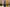 Three tall candles in white, blue, and gold on a table with a decorative background.